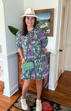 Load image into Gallery viewer, Green and purple floral printed mini dress. Puff sleeves, triple front closure, babydoll style with pockets. Light weight cotton and lined. Personally did not need tank under ties, but could be worn.
True to size, wearing size small.
Good for bump, post bump or no bump.
Step into whimsical elegance with this green and purple floral printed mini dress, perfect for breezy days and effortless style. Designed in a flattering babydoll silhouette, this dress features puff sleeves for a romantic touch and