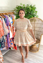Load image into Gallery viewer, Dallas mini dress with ruffle detailing on neck, arms and waistline. Slight smocking and pink tuck detailing at neck. Double lined light weight cotton with pockets. Double back tie with cotton rope and tassels. Wearing size small, sized up from x-small for bust.