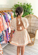 Load image into Gallery viewer, Dallas mini dress with ruffle detailing on neck, arms and waistline. Slight smocking and pink tuck detailing at neck. Double lined light weight cotton with pockets. Double back tie with cotton rope and tassels.  Wearing size small, sized up from x-small for bust.