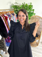 Load image into Gallery viewer, Black poplin mini dress with double ruffle fly away sleeves with long sleeves. Ruffle detailing elastic at wrist for arm placement. Split neck and a-line cut. Cotton poplin.  True to size, fits roomy, wearing size small.  Good for bump, post bump or no bump!
