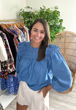 Load image into Gallery viewer, Smocked bodice chambray blouse with ruffle detailing at yoke. Elastic wrists for sleeve placement. Back keyhole closure. Light weight cotton blend.  True to size, wearing size small.
