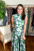 Load image into Gallery viewer, Green and silver tulip and palm printed jumpsuit. Mock collar, shoulder pads and empire waist. Flare pants and structured bodice. Back zipper closure. Poly silk blend.  True to size, wearing size small.
