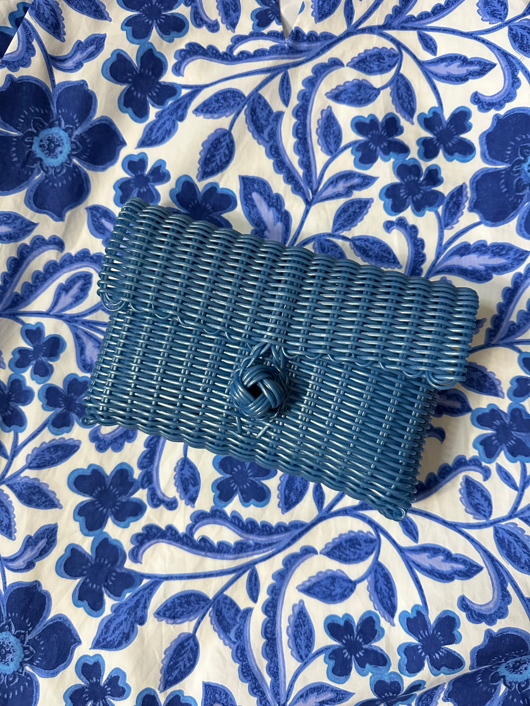 Blue woven clutch with front knot closure. Woven plastic, perfect for spring and summer.