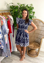 Load image into Gallery viewer, Indigo mini dress with white and blue hand block print pattern. Smocked bodice, ruffle flutter sleeves, ruffle at empire and gathered skirt. Back keyhole closure. Light weight cotton.   True to size, wearing size x-small.
